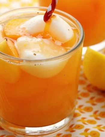 Refreshing Peach Lemonade in a glass with fresh peaches and lemons