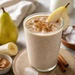Creamy pear cinnamon smoothie served in a glass with a cinnamon stick on top