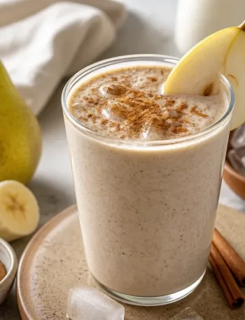 Creamy pear cinnamon smoothie served in a glass with a cinnamon stick on top